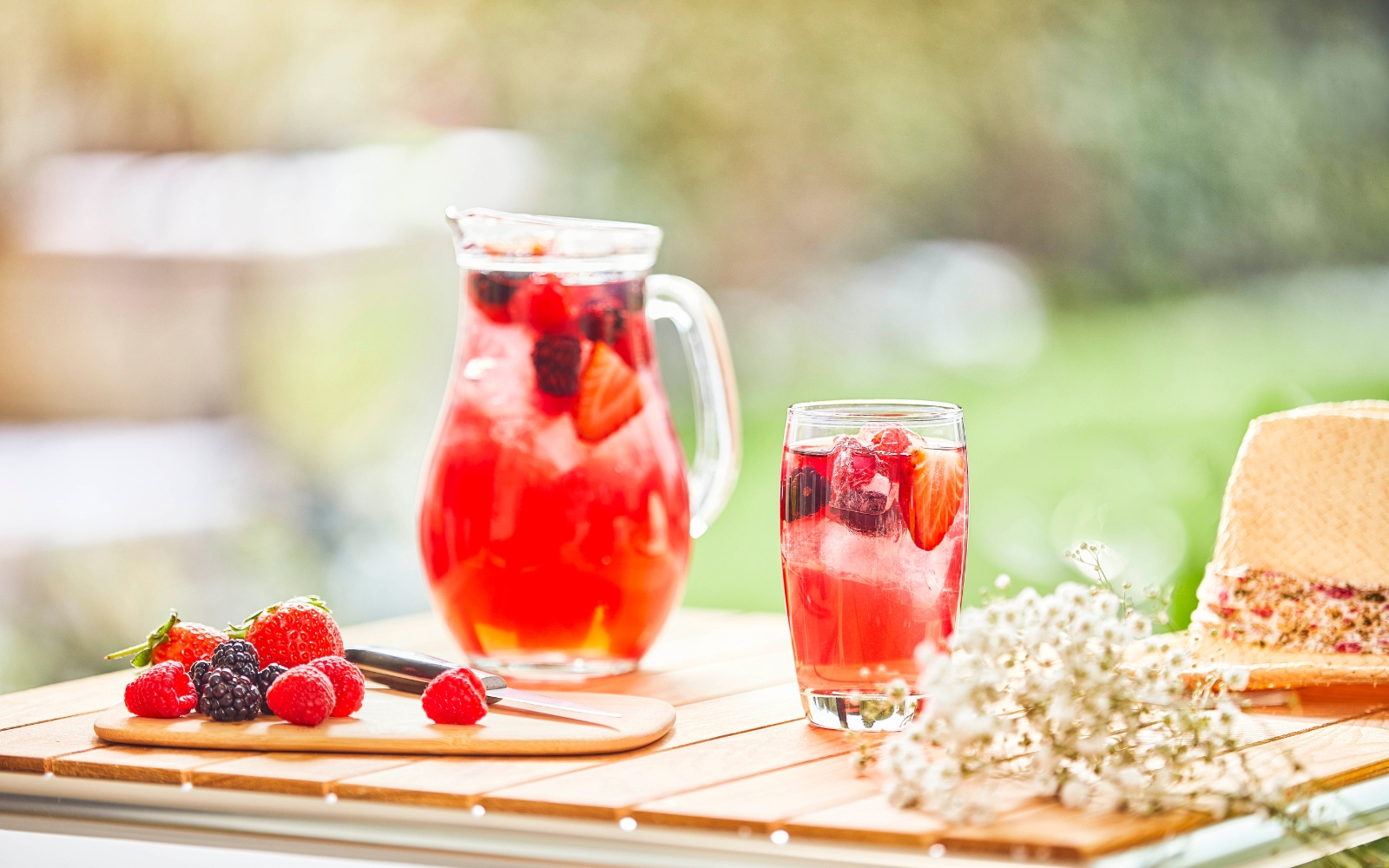 Tisch mit Glasteekanne, Teeglas und Beeren