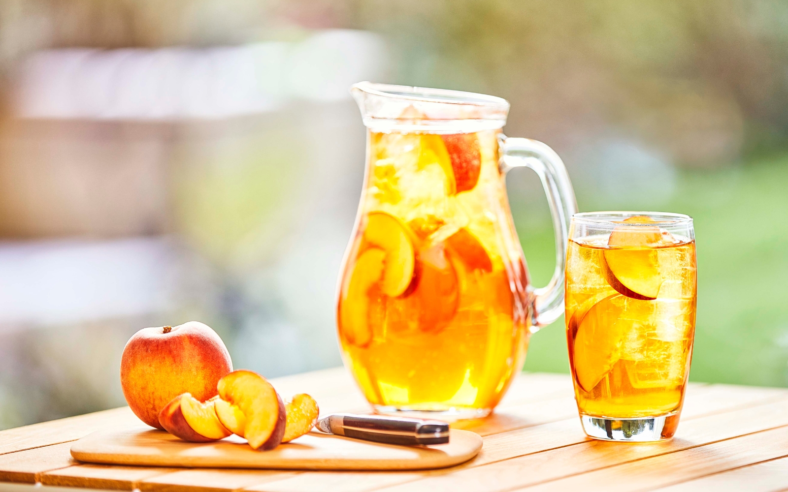 Tisch mit Glasteekanne, Teeglas und Pfirsichspalten