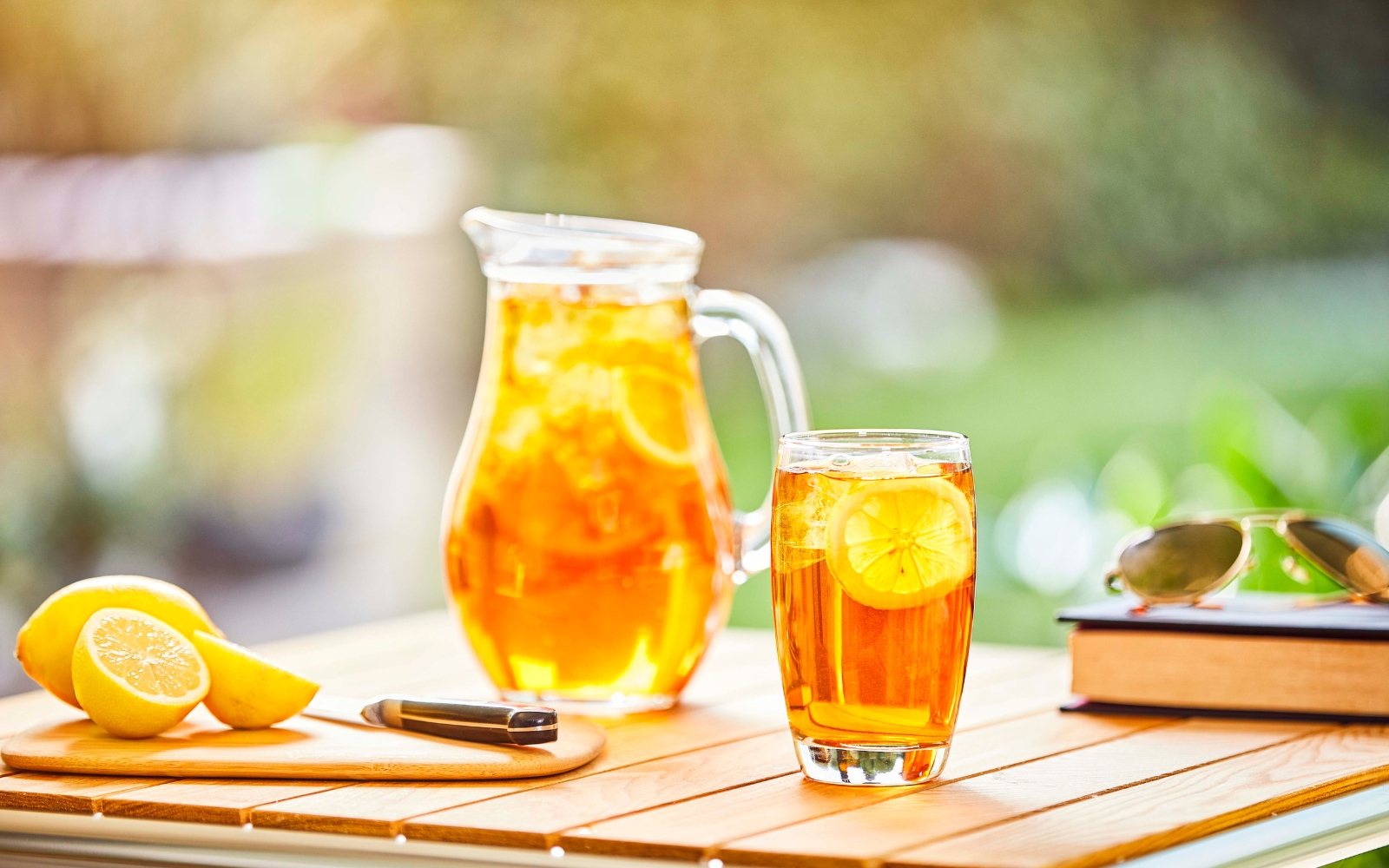 Tisch mit Glasteekanne, Teeglas und Zitronen