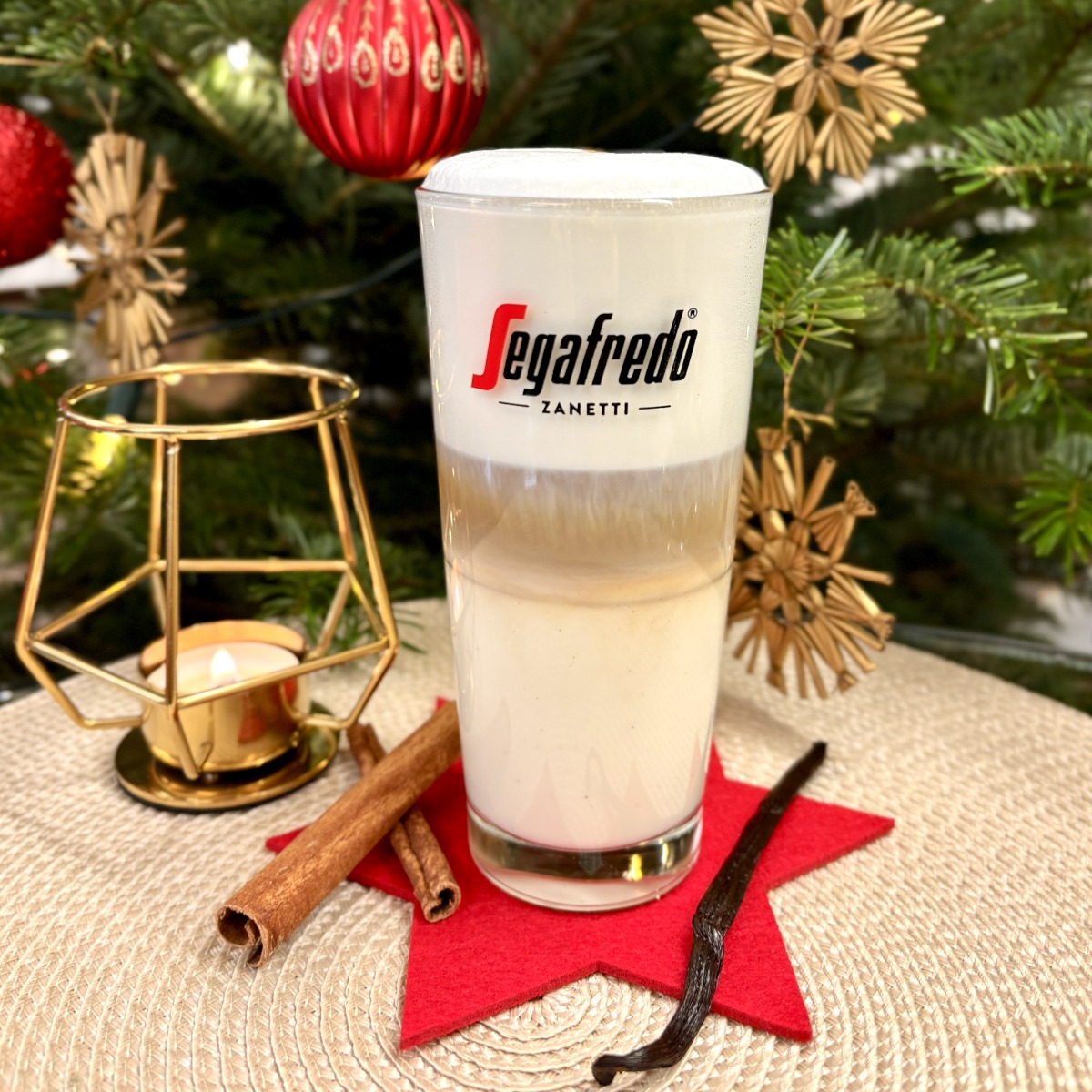 ein Latte Macchiato im Glas vor weihnachtlicher Dekoration